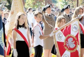 Poczet sztandarowy na tle salutujących żołnierzy