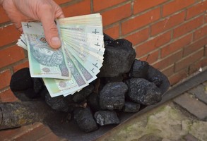 Ręka z pieniędzmi nad węglem